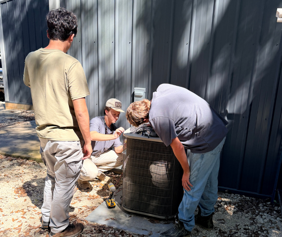 Residential AC repair showing three men working on an AC unit
